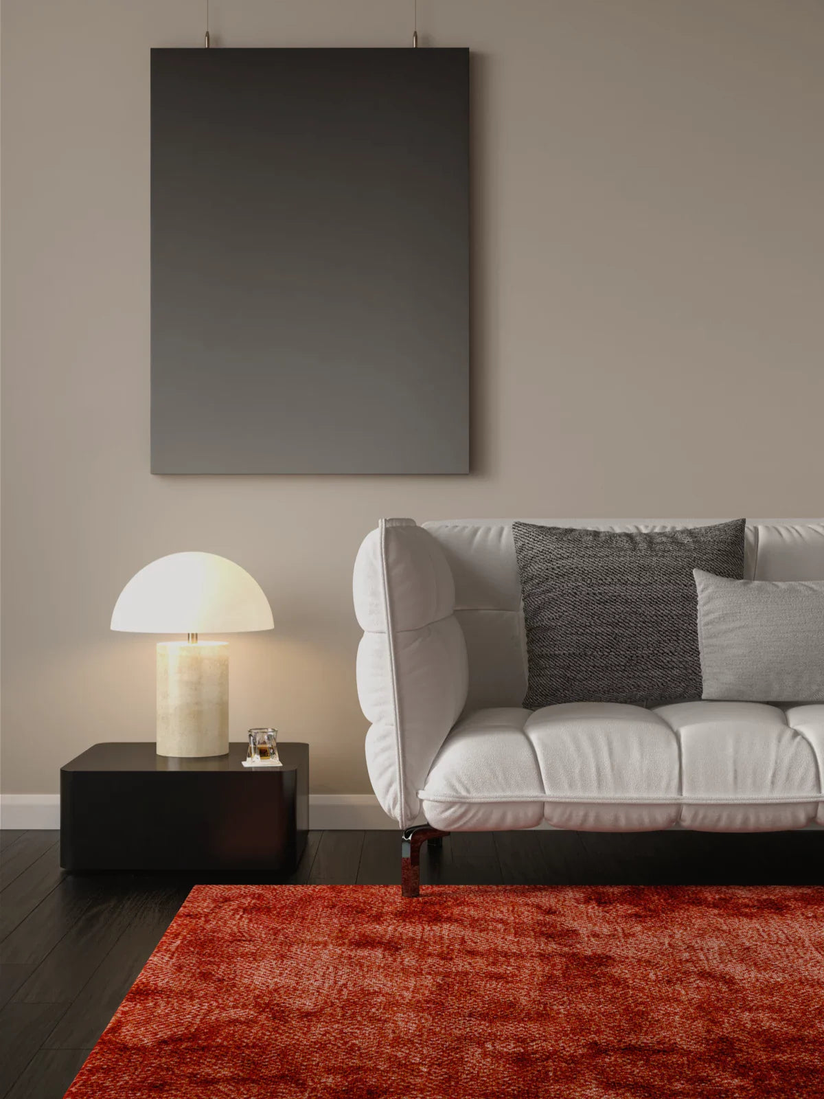 A modern and sophisticated living space featuring a deep red textured rug, a sleek white sofa with black and gray accent pillows, and a minimalist black side table with a stylish lamp.