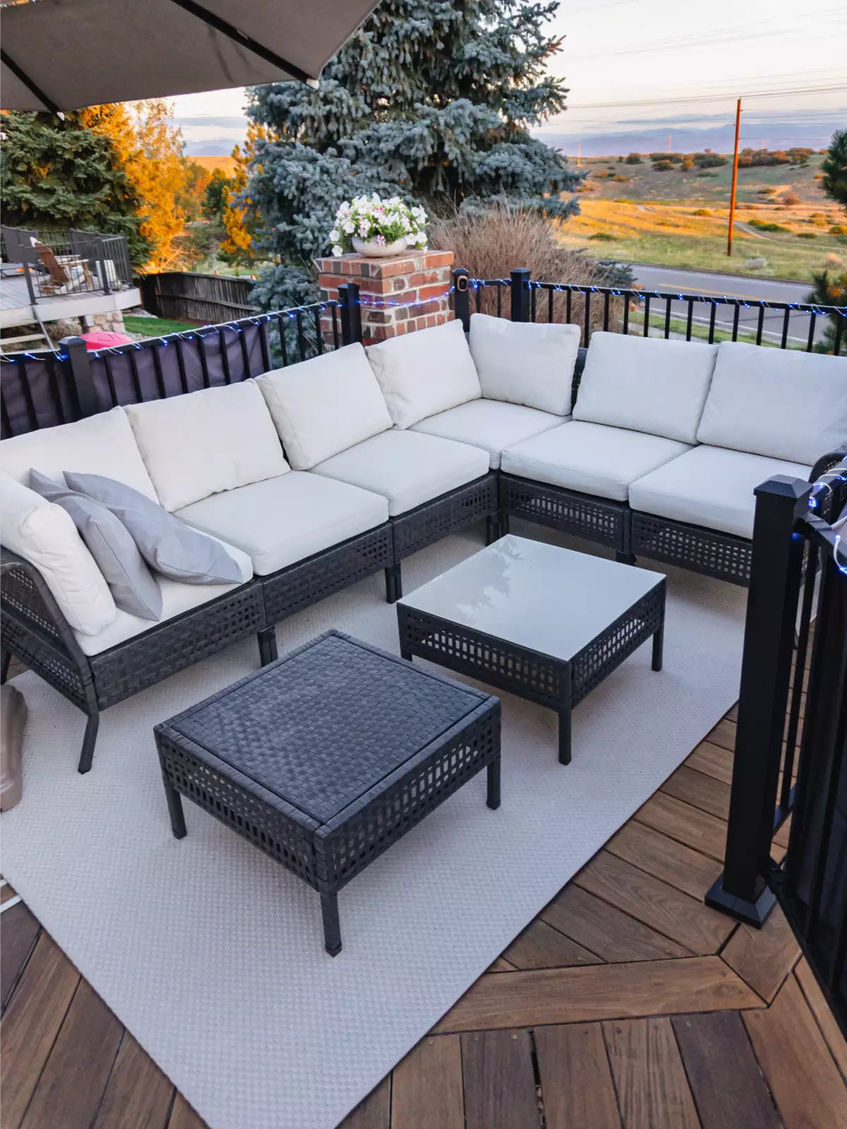 Stylish outdoor patio with a weather-resistant, washable rug under a modern wicker sectional sofa, creating a cozy and elegant terrace setting.
